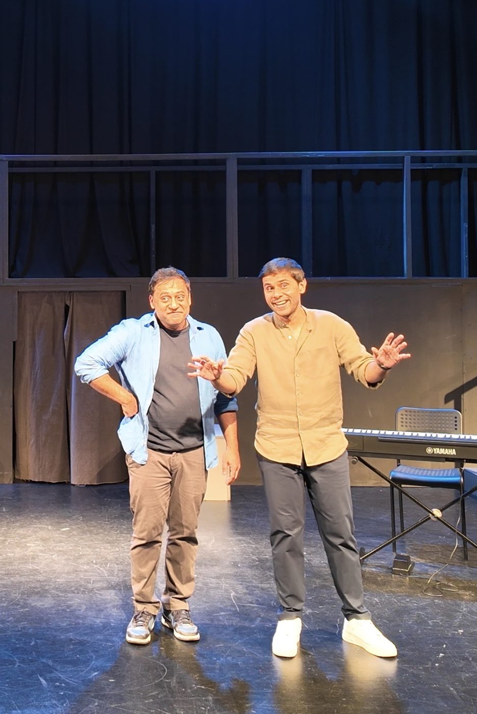 Two improvisers posing on stage with a keyboard behind them