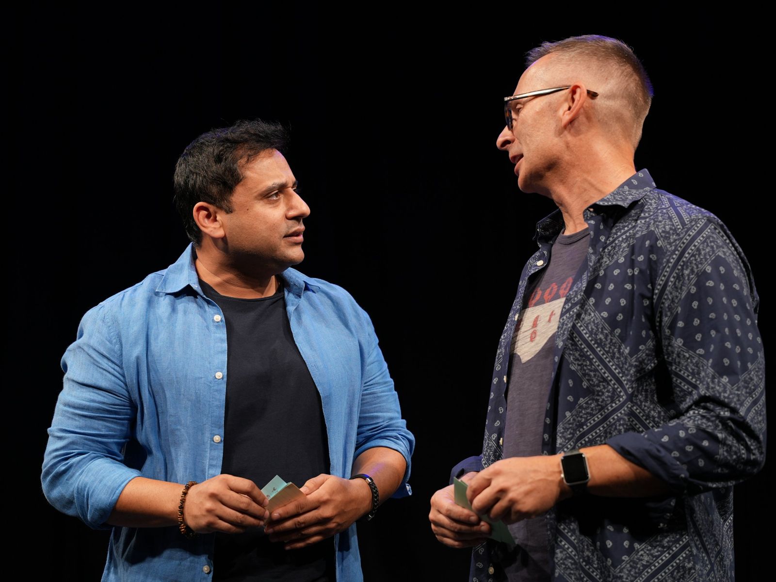Improvisers on stage holding audience suggestion cards