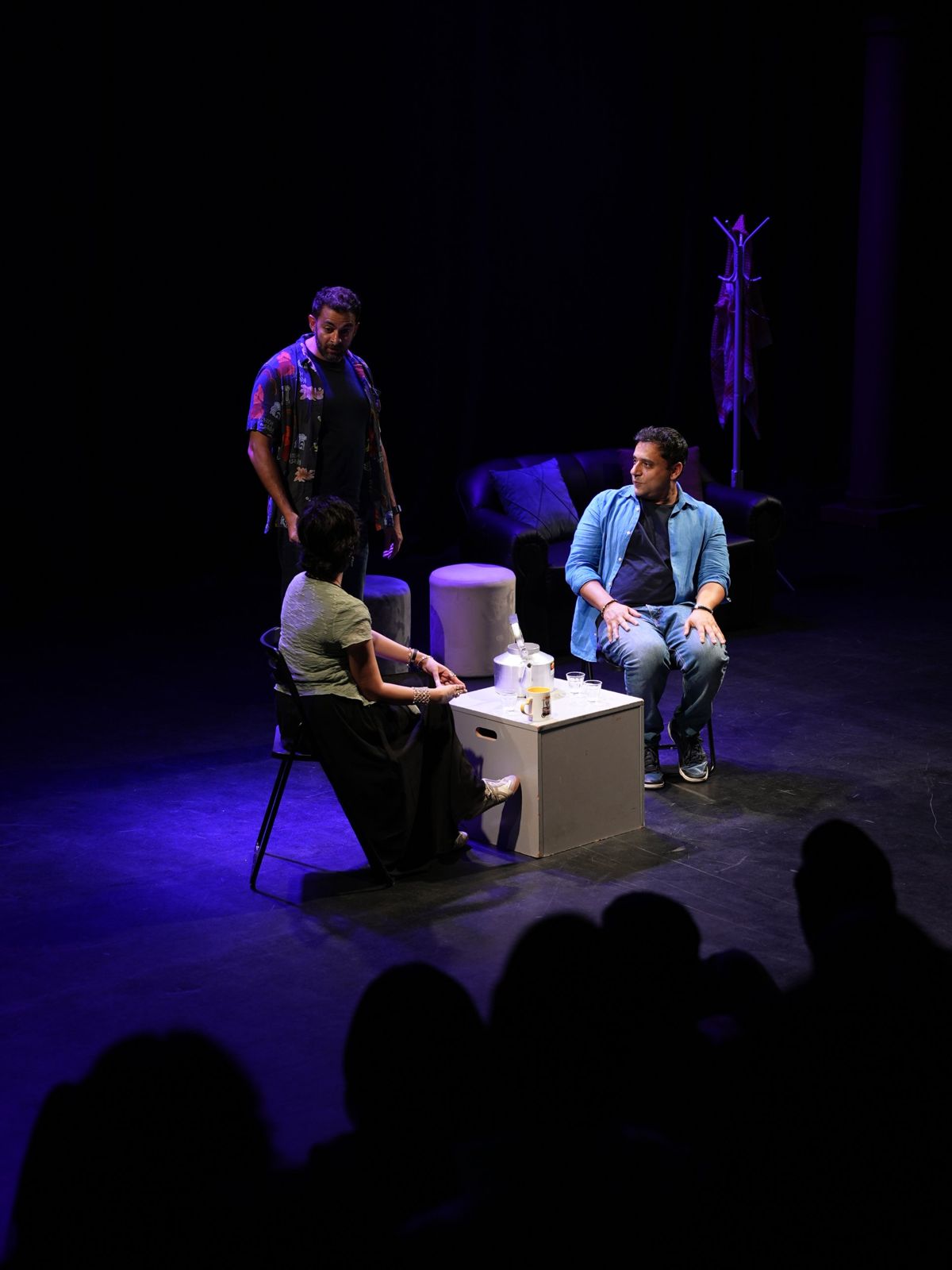 Three performers around the karak table during a live show